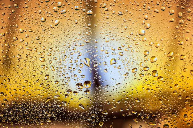 Abstract texture. Water drops on glass with orange harbor