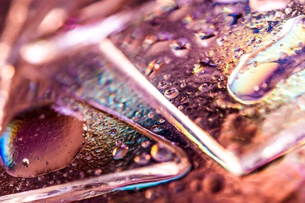 Photo abstract trendy holographic background in the style of the 80-90s. real texture of broken glass or ice and water drops in bright acid colors. synthwave vaporwave webpunk massurrealism aesthetics.