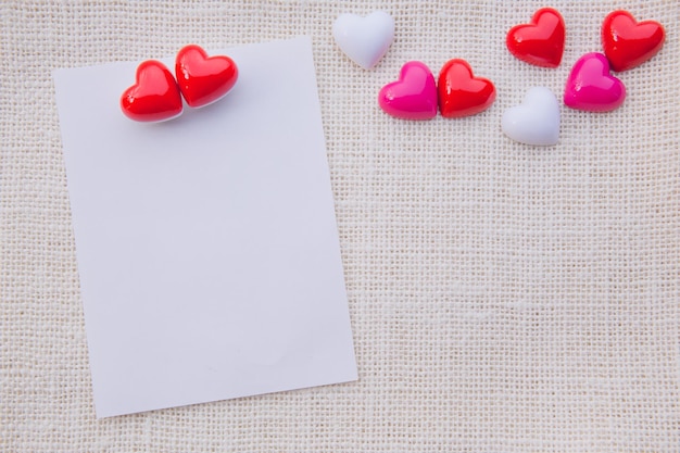 写真 グラフィック デザインの白い布リネン テクスチャに紙でバレンタインデーの赤いハートを抽象化またはテキスト メッセージの愛の概念を追加