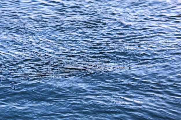 Photo abstract water surface closeup with small plain ripples and selective focus