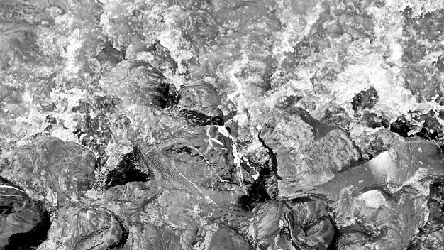 Photo abstract water wave at stone coast - monochrome