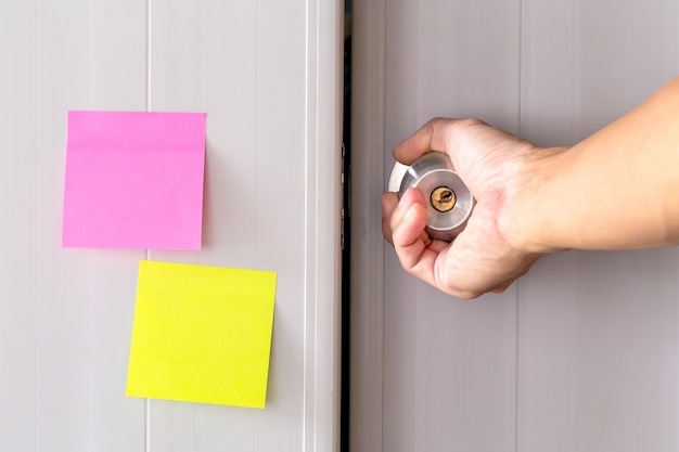 Abstract white door with metal doorknob is lock and sticker paper note on door.