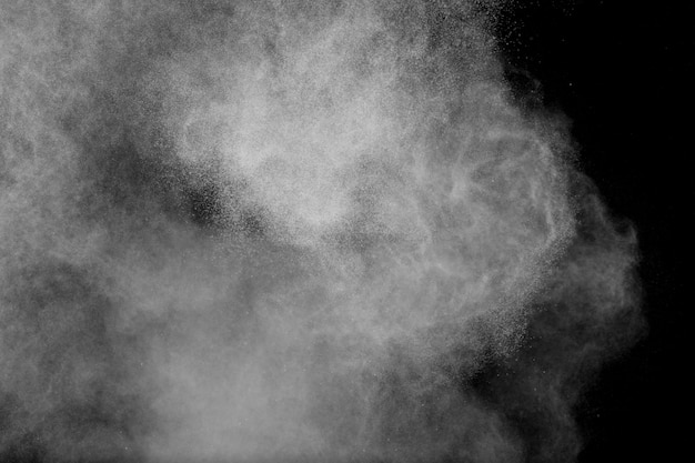 Abstract white powder explosion. White dust debris isolated on black background.