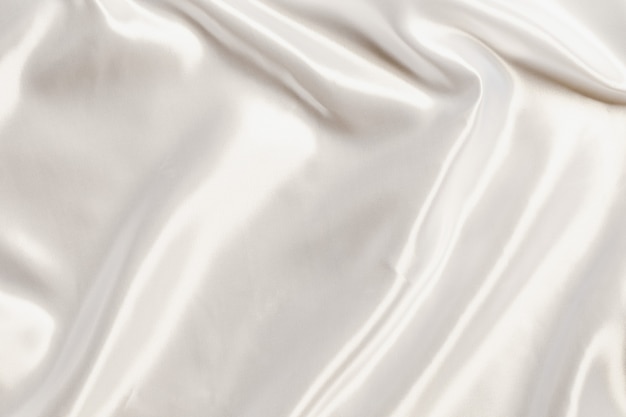 Photo abstract white satin silky cloth for background, fabric textile drape with crease wavy folds.with soft waves,waving in the wind.