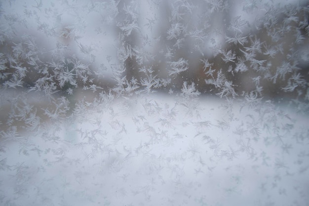 ガラスの上の抽象的な冬の背景の雪粒