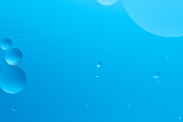 Abstracte afbeelding met blauwe bubbels van verschillende maten op een lichtblauwe achtergrond die een serene en minimalistische uitstraling creëert