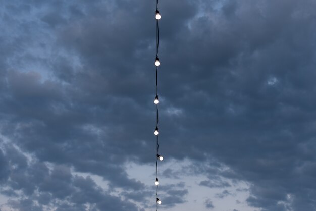 Abstracte blauwe achtergrond voor ontwerp met wolken en slinger van gloeilampen