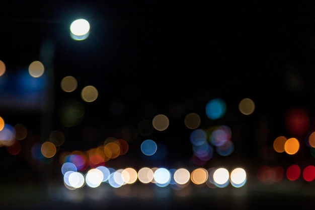 Abstracte bokeh achtergrond van donkere straat met lichte auto en straatlantaarns Stadsleven intreepupil lichten van stadsgezicht stijlvol kleurrijk
