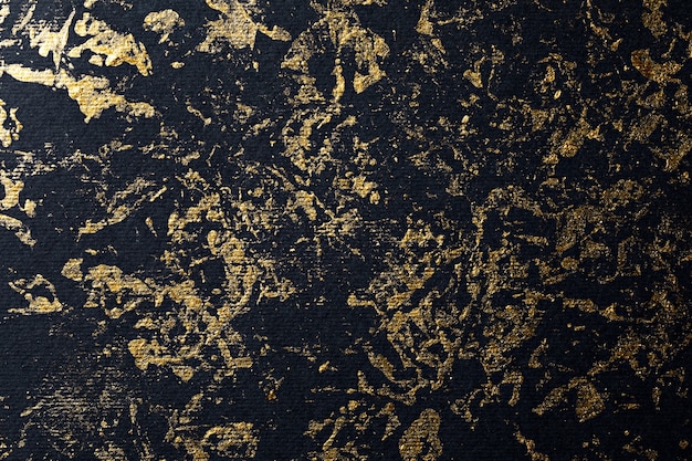 Abstracte gouden verf op zwart geweven papier