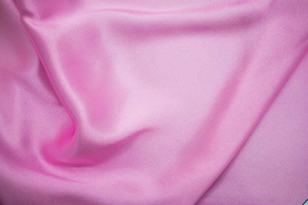 Abstracte roze satijn zijdeachtige doek stof textiel draperen met vouw golvende plooien achtergrond