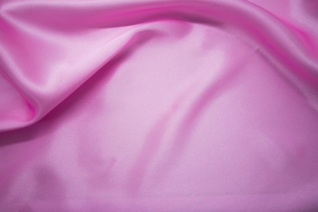 Abstracte roze satijn zijdeachtige doek stof textiel draperen met vouw golvende plooien achtergrond