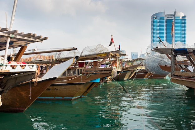 Горизонт зданий Абу-Даби со старыми рыбацкими лодками на фронте