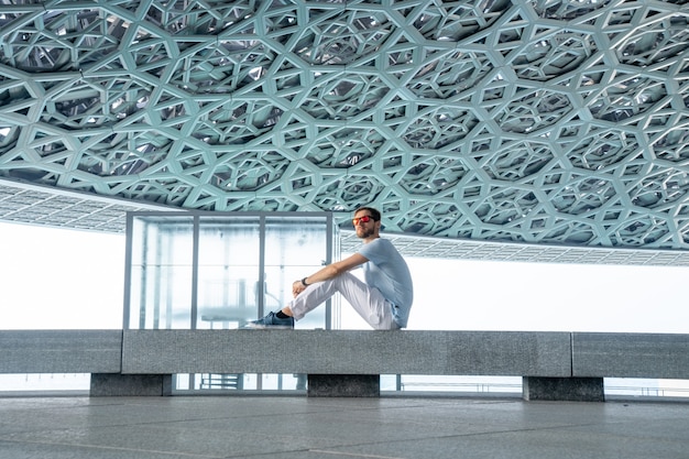 Abu Dhabi, United Arab Emirates, MAY 20, 2020: Young man sitting in louvre in Abu Dhabi exploring the art.