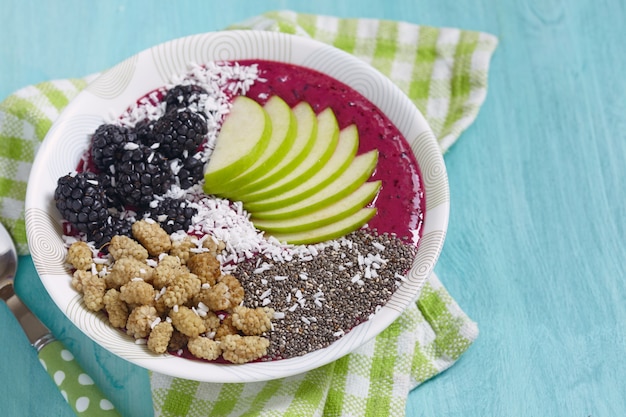 Acai bowl smoothie gegarneerd met appels, bessen, kokos en chiazaad