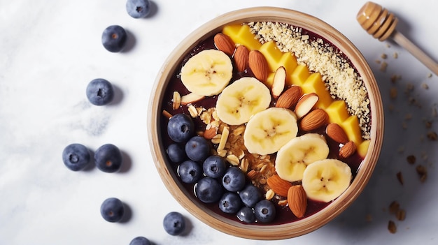 Acai bowl topped with banana slices blueberries almonds and granola on a marbled surface