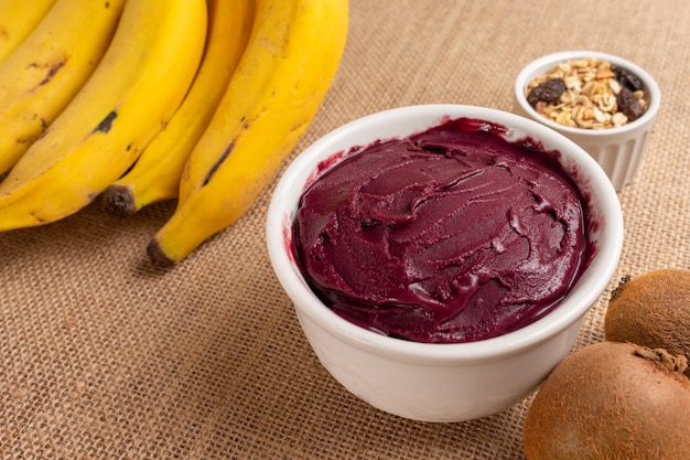 Acai bowl with banana, kiwi and cereal on burlap cloth