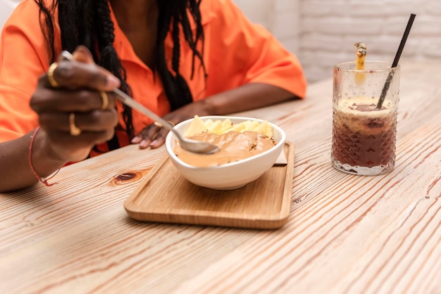 Acai bowl woman eating morning breakfast at cafe Organic raw vegan healthy food