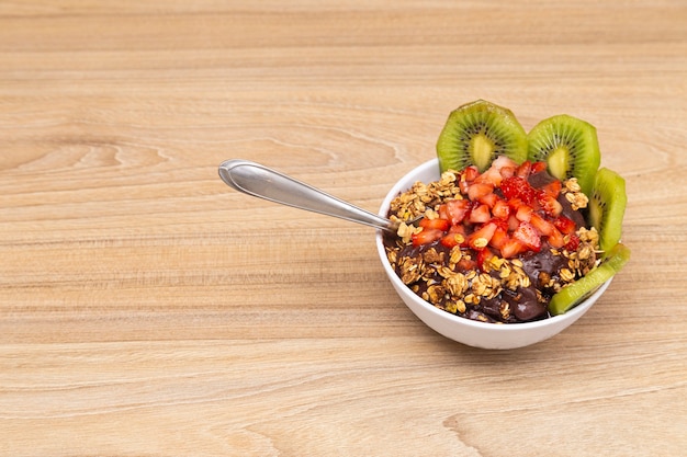 Acai bowl, on wooden table with spoon to eat.