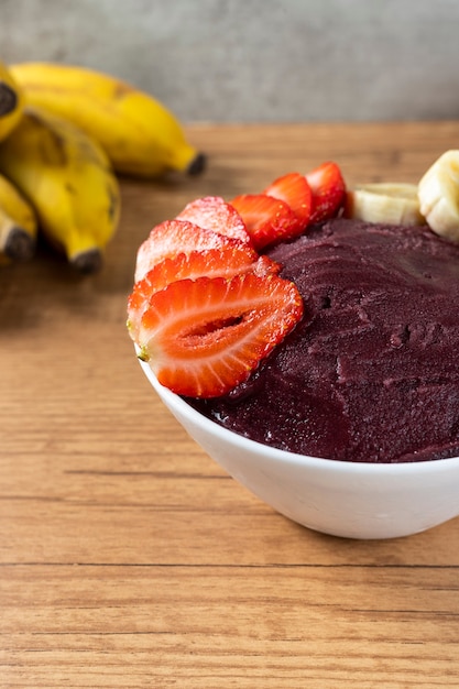 Acai, Braziliaanse bevroren Acai-bessenroomijskom met aardbeien en bananen. met fruit op houten tafel. Zomermenu vooraanzicht