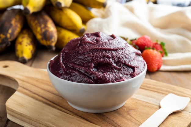 Acai, 브라질 냉동 Acai 베리 아이스크림 그릇에 딸기와 바나나. 나무 테이블에 과일. 여름 메뉴 전면보기