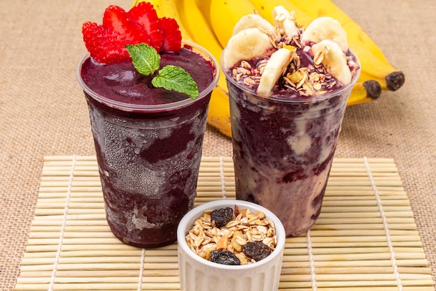 Acai cups with fruits and cereal on the table ready to eat in summer weather.