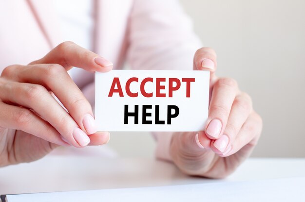 Accept help is written on a white business card in a woman's hands