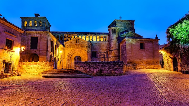 Access esplanade to medieval church illuminated at night by streetlights. Santillana del mar.