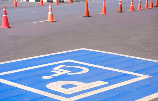 Accessible wheelchair parking sign with row of traffic cone on street surface