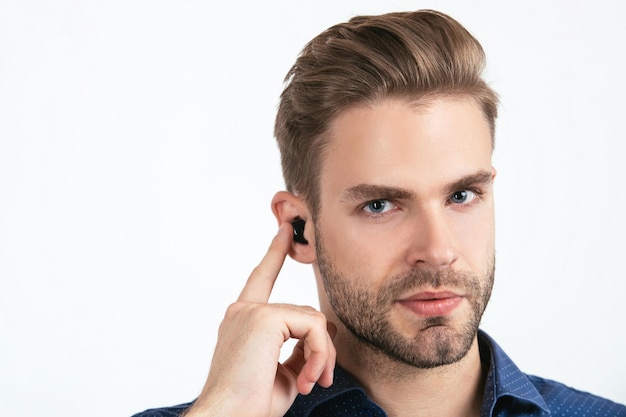 Accessoire voor Bluetooth-headsetapparaat. nieuwe technologie. succesvolle ongeschoren man. wendbaar bedrijf. knappe man met draadloze koptelefoon. zakenman gebruik bluetooth oortelefoons. trendy mannen geïsoleerd op wit.