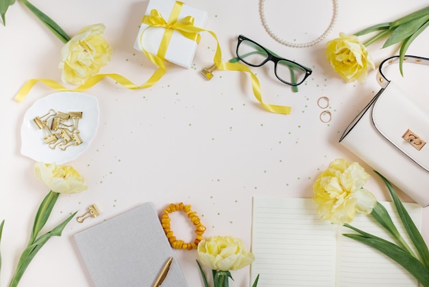 Accessoires voor een vrouwelijke blogger op een lichte achtergrond met een handtas lentebloemen gele tulpen