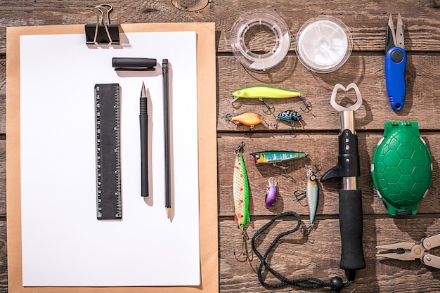 Foto accessoires voor het vissen op de achtergrond van hout. haspel, vislijn, dobber, nethaken, kunstaas om te vissen. bovenaanzicht. stilleven. kopieer ruimte