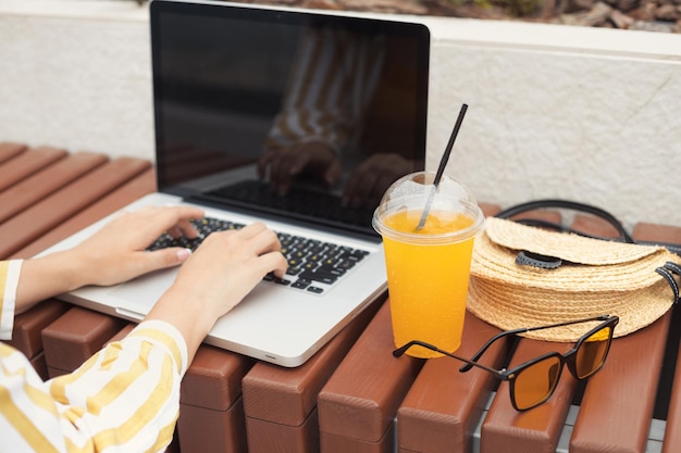 Foto accessori donna d'affari laptop cool succo d'arancia borsa di paglia e occhiali da sole gialli all'aperto