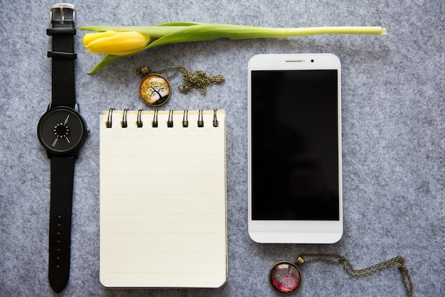 Accessories for work: notebook, phone, clock on gray