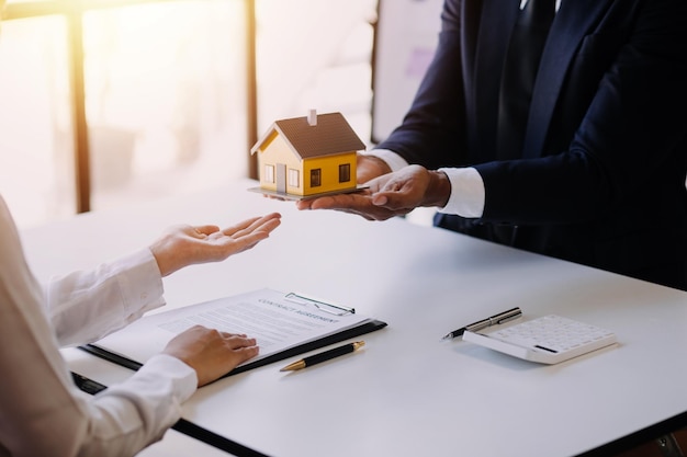 Accountant businessman real estate agent Asian business woman handing keys to customers along with house after customers to sign