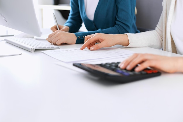 Accountant checking financial statement or counting by calculator income for tax form hands closeup