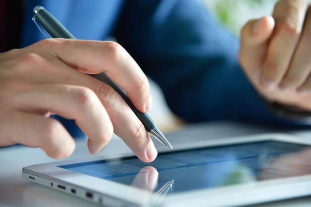 Photo accountant checks business report on digital tablet screen