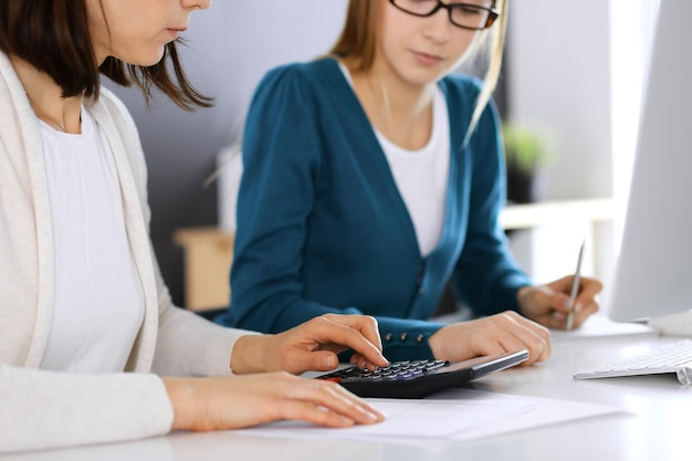 Foto accountant die financiële verklaring controleert of door rekenmachineinkomen telt voor de close-up van de handen van het belastingformulier