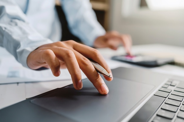 Accountant gebruikt rekenmachine en computer met pen op bureau in kantoor. financieel en boekhoudconcept