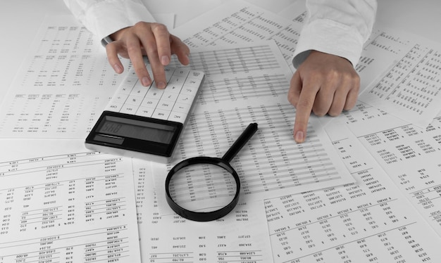 Accountant holding a calculator pointing at numbers on financial documents Soncept of finance search and accounting