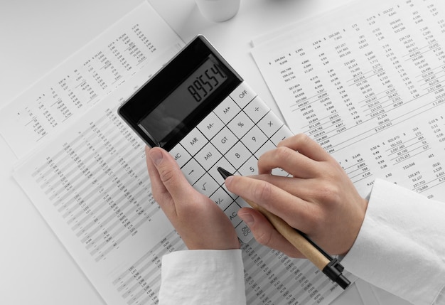 Фото Бухгалтер с помощью калькулятора в офисе на белом фоне с финансовым отчетом вид сверху