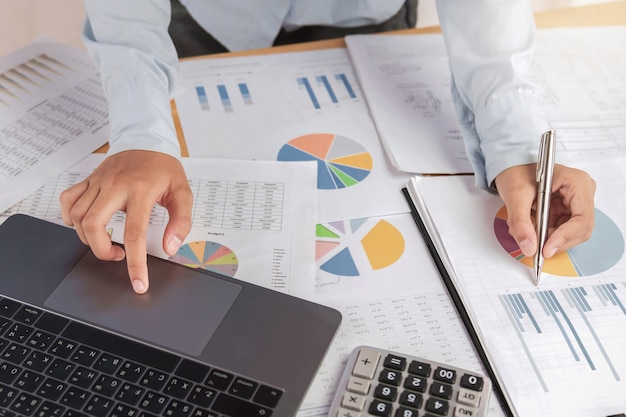 Accountant using laptop with pen on desk in office. finance and accounting concept