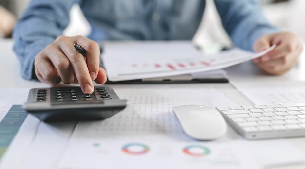Бухгалтер, работающий с финансовыми инвестициями на калькуляторе, анализирует рост бизнеса и рынка на графике данных финансовых документов