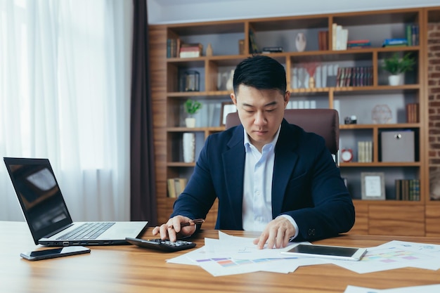 Accountantauditor werkt in een klassiek kantoor berekent financiële rapporten Aziatische zakenman werkt met computer- en documentenpapier