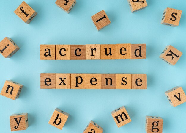 Photo accrued expense word on wooden block. flat lay view on blue background.