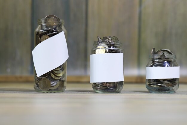 Photo accumulated coins stacked in glass jars on the floor