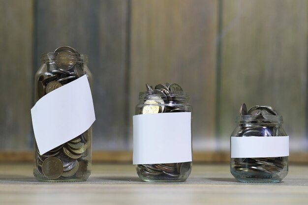 Photo accumulated coins stacked in glass jars on the floor