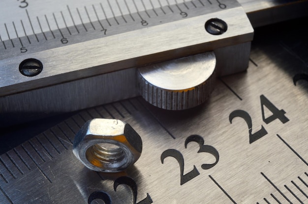 Accurate measuring tool caliper and metal ruler lie in place with nuts closeup