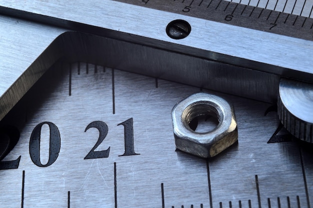 Accurate measuring tool caliper and metal ruler lie in place with nuts closeup