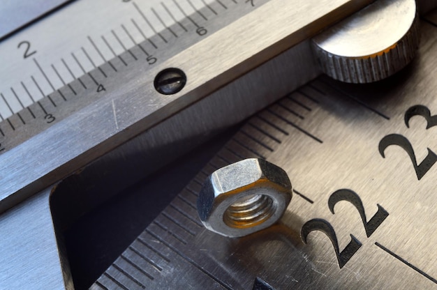 Foto il calibro preciso dello strumento di misurazione e il righello in metallo si trovano in posizione con il primo piano dei dadi