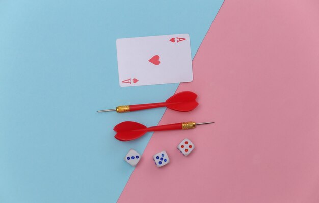 Ace of hearts, dice and darts on pink blue pastel background. Top view